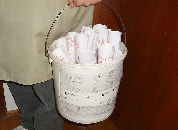 Foto einer Kunststoffeimers gefüllt mit gerollten Zeichnungen