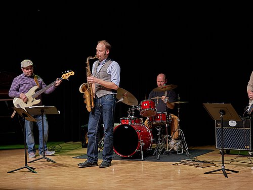 vier Musiker an ihren Instrumenten auf der Bühne