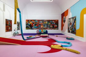 Blick in den großen Saal der Kunsthalle, der mit Teppichboden in Rot und  Pink ausgelegt ist. An den teils farbigen Wänden hängen großformatigen Gemälde von Monika Michalko