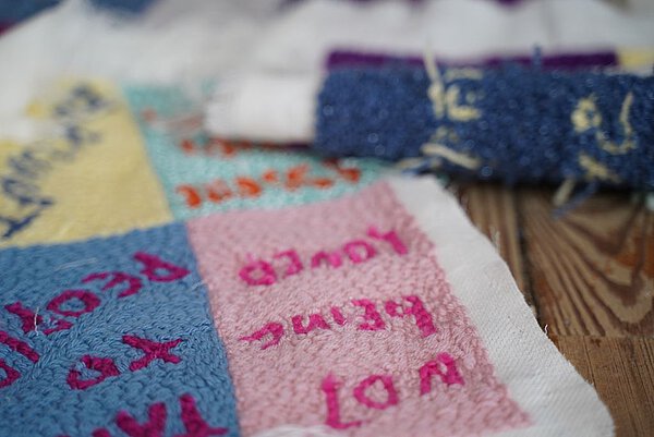 Worte auf Gestricktes gestickt