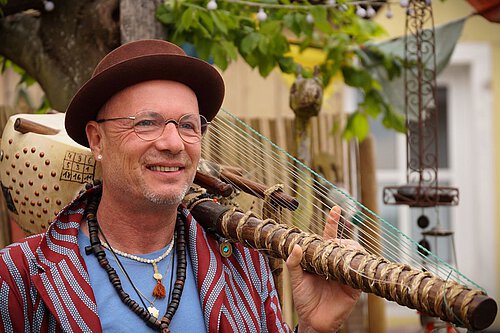 Mann mit Hut und Kora-Instrument über der Schulter