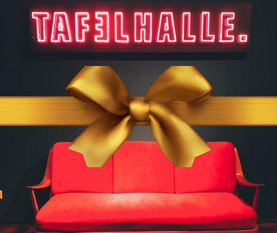 Rotes Sofa mit Holzarmlehnen vor schwarzer Wand, darüber leuchtendes Schild mit Text 'TAFELHALLE.'