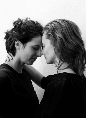 schwarz/weiß-Foto: zwei Frauen sehen sich lächend an, die Gesichter ganz nah beieinander
